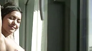 一位身材娇小的美艳亚洲熟女脱下内衣，露出丰满的乳房。